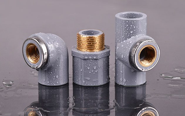 CPVC couplings and fittings with brass flanges on reflective surface.