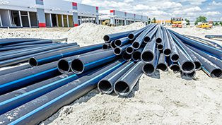 Stack of blue PVC pipes, exemplifying durability and longevity, at a construction site.