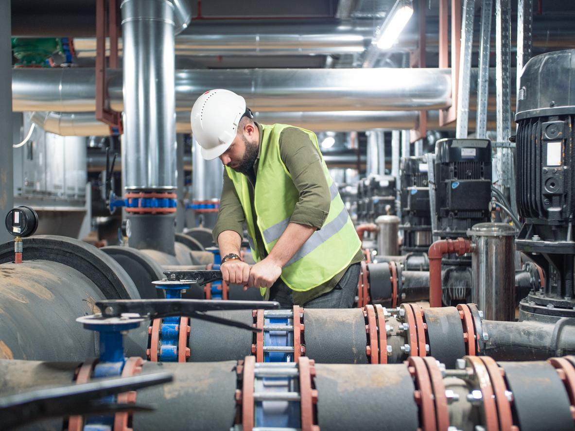 Engineer using a valve selection guide while working on valves in a factory.